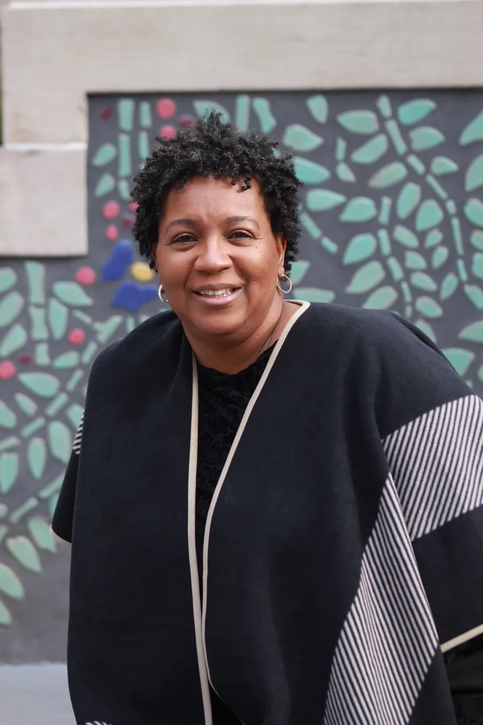 Teresa Pressley smiling in front of a leaf mural