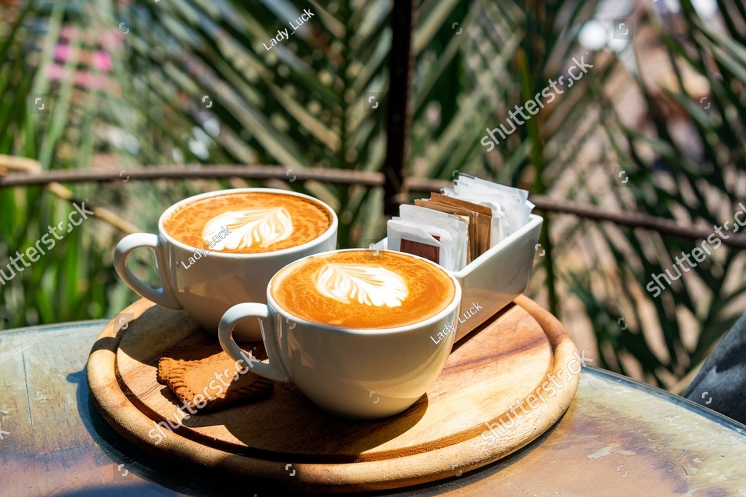 Two lattes side by side on a wooden tray